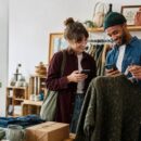 Two shoppers using secondhand shopping apps in a UK vintage clothing shop